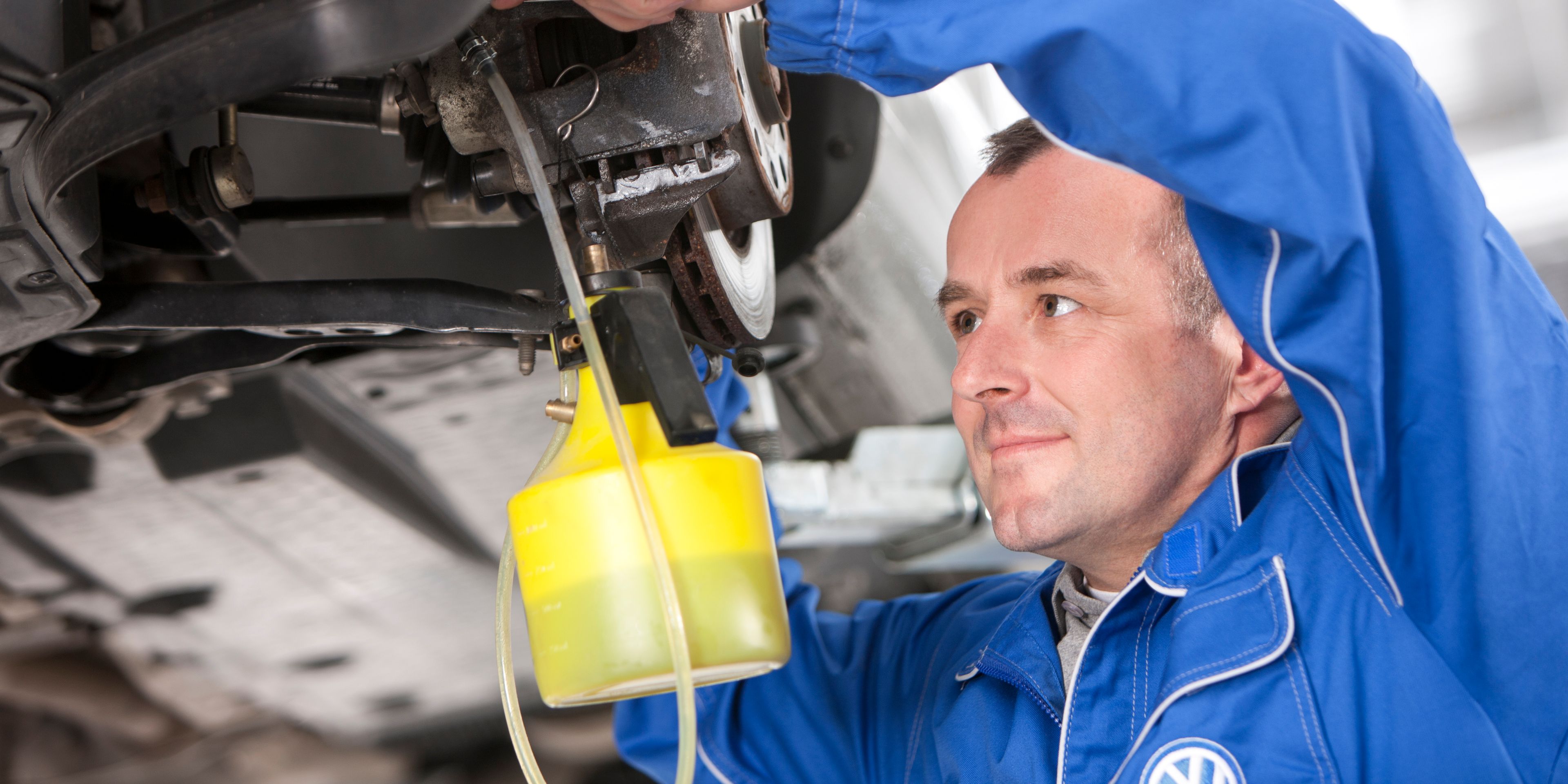VW Mechaniker füllt VW Bremsflüssigkeit ein