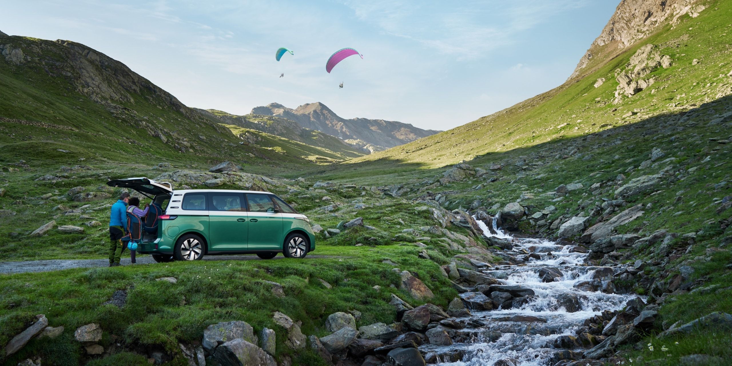 Volkswagen ID. Buzz stojí u horského potoka s otevřenými zadními dveřmi