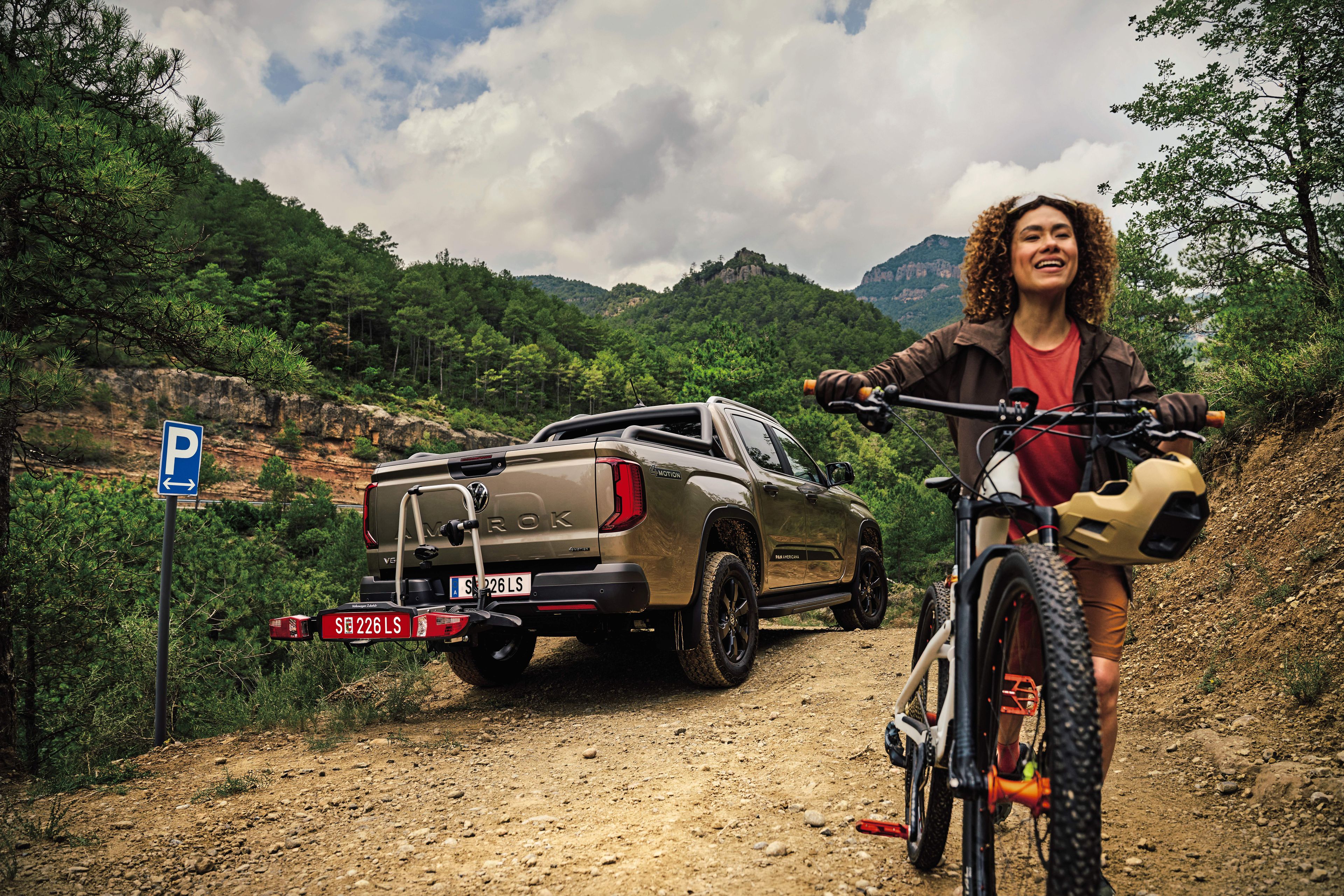 Volkswagen Amarok parkuje v lese, žena s horským kolem odjíždí