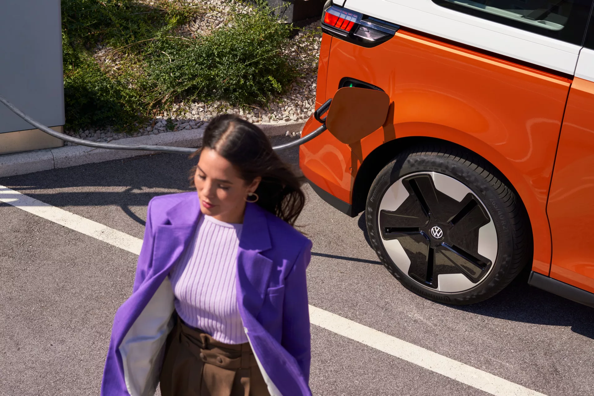 Frau entfernt sich von einem ladenden VW ID. Buzz