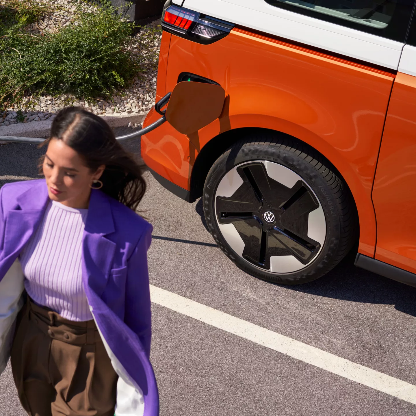 Frau entfernt sich von einem ladenden VW ID. Buzz