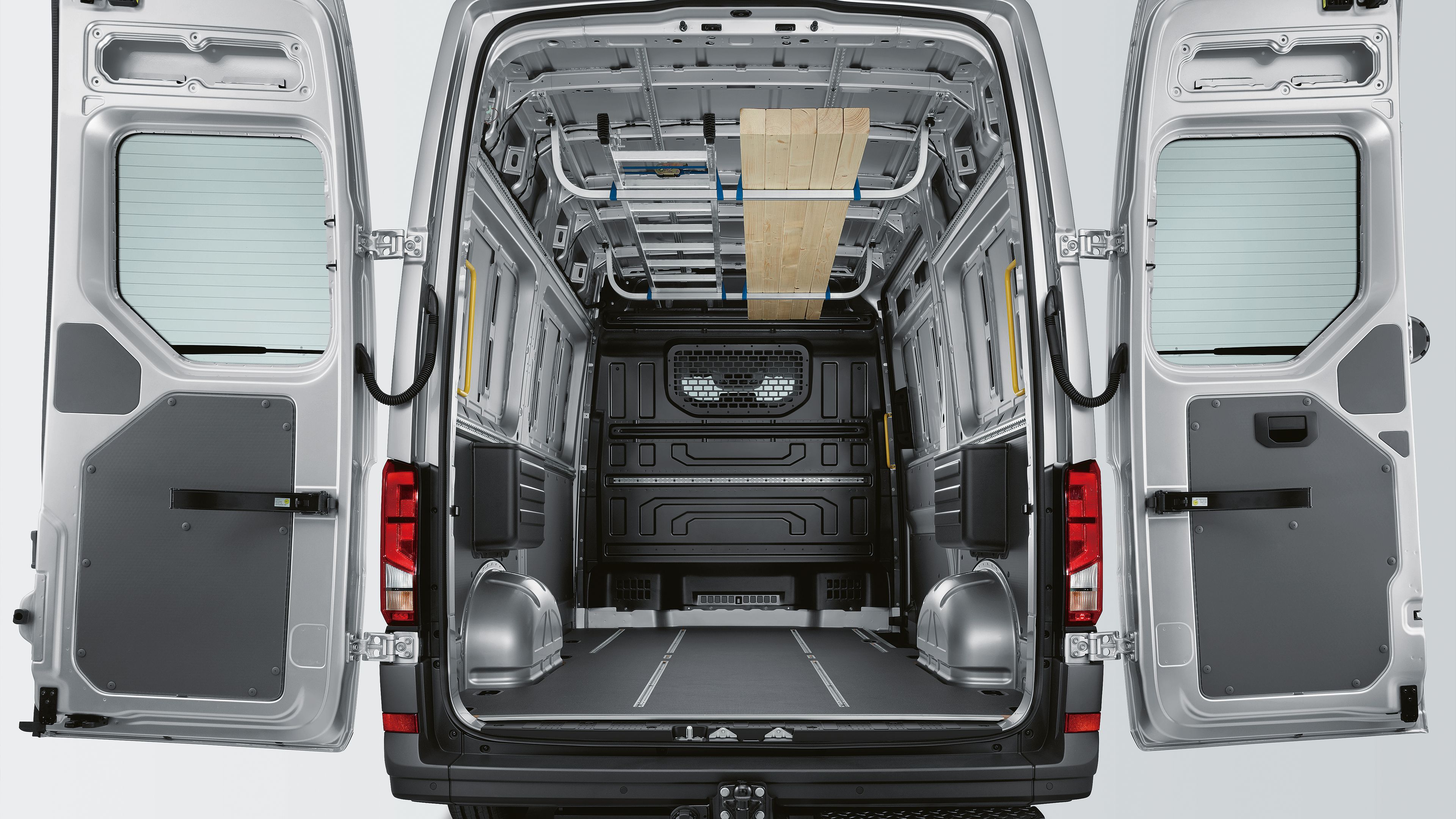 Pohled do nákladového prostoru modelu Volkswagen Užitkové vozy Crafter Skříňový vůz. Je vidět dělicí přepážka s oknem a ochranou mříží.