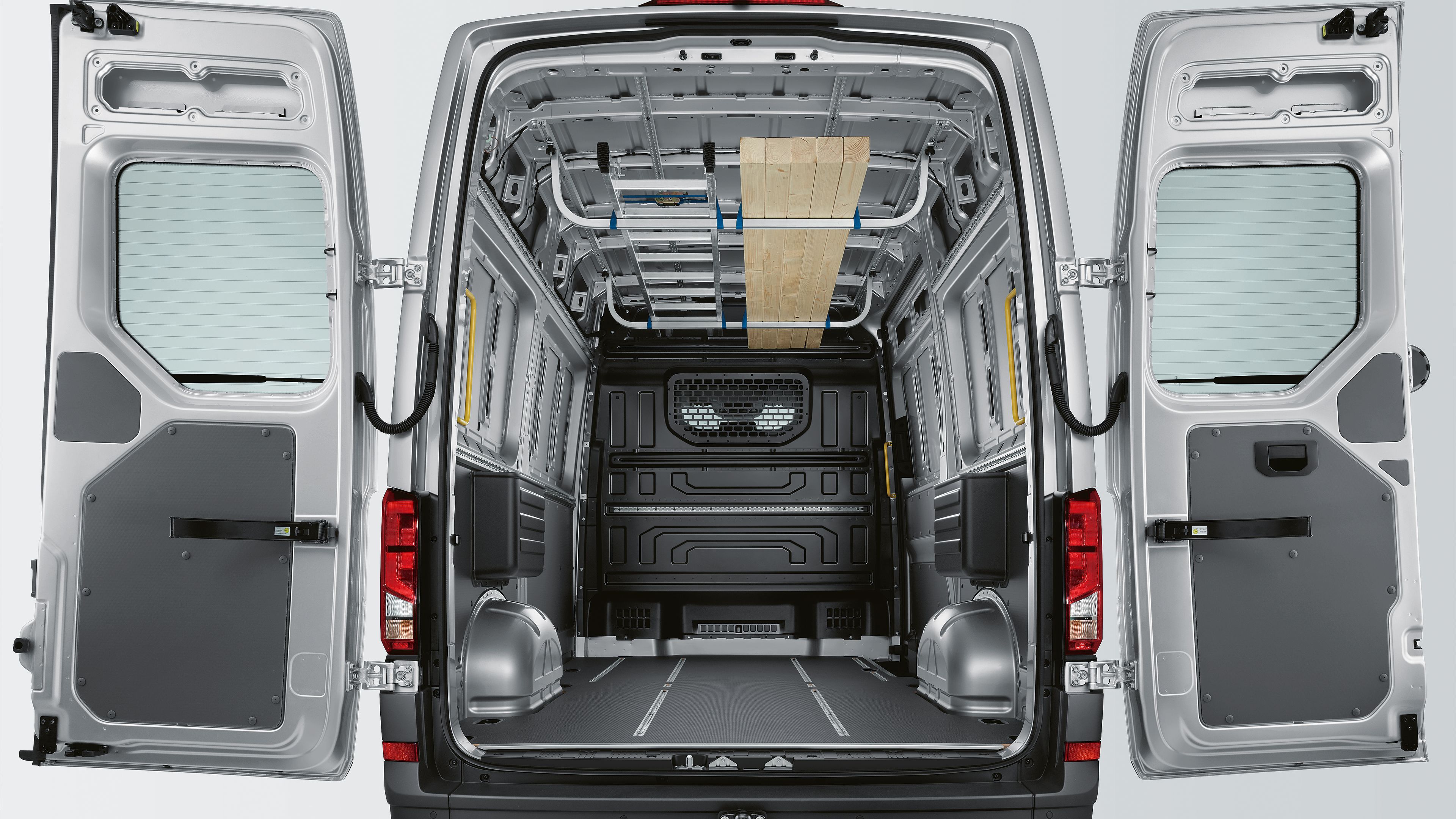 Pohled do nákladového prostoru modelu Volkswagen Užitkové vozy Crafter Skříňový vůz. Je vidět dělicí přepážka s oknem a ochranou mříží.