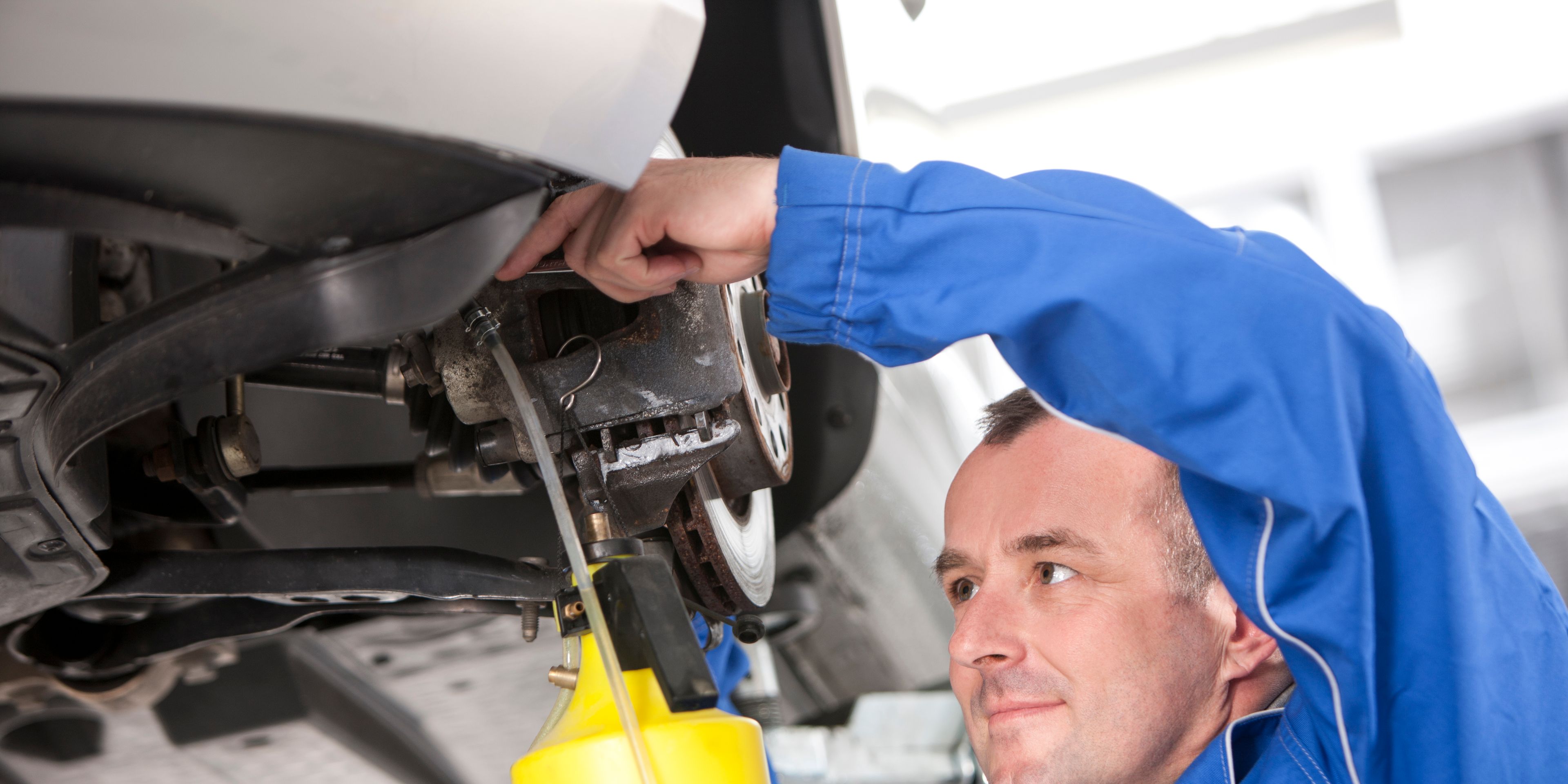 VW Mechaniker füllt VW Bremsflüssigkeit ein