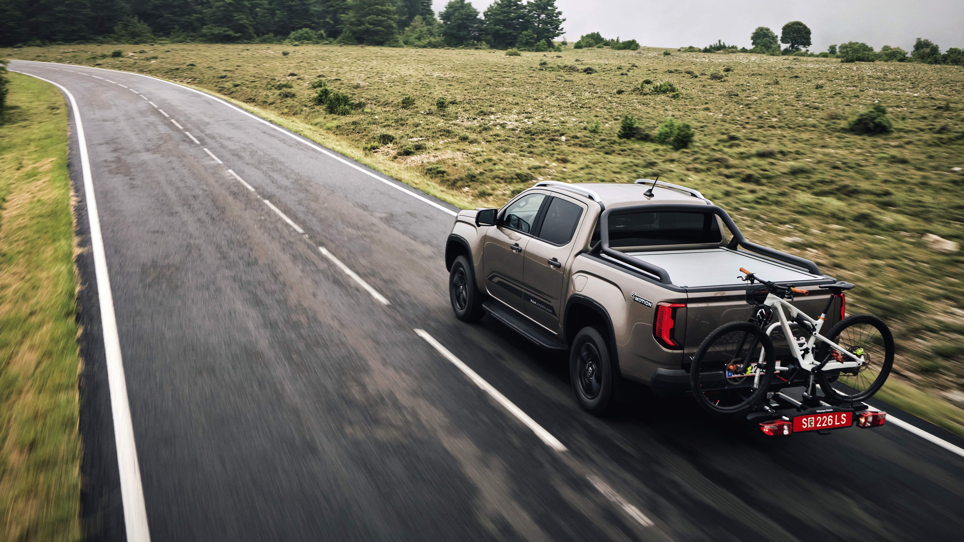 Volkswagen Amarok s nosičem kol jezdí po silnici za mokra