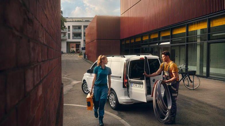 Weißer VW Caddy Kastenwagen fährt durch Stadt