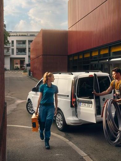 Weißer VW Caddy Kastenwagen fährt durch Stadt