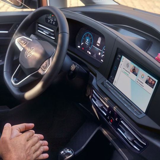 Žena a muž sedí v užitkovém voze Volkswagen. Žena se dotýká displeje.